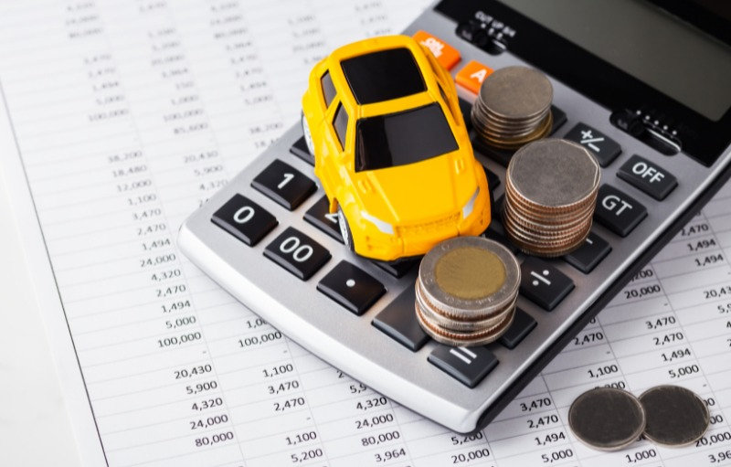 Toy yellow car on a calculator with stacked coins